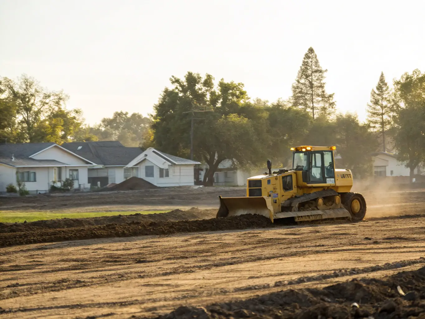 A Yanmar excavator removing brush and debris from a residential lot, highlighting the process of clearing unwanted vegetation and preparing the land for development.